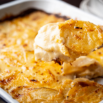 Potatoes au gratin casserole with spoon in casserole dish