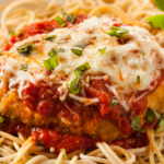 Chicken coated in breadcrumbs with tomato sauce and parmesan cheese melted on top over spaghetti noodles