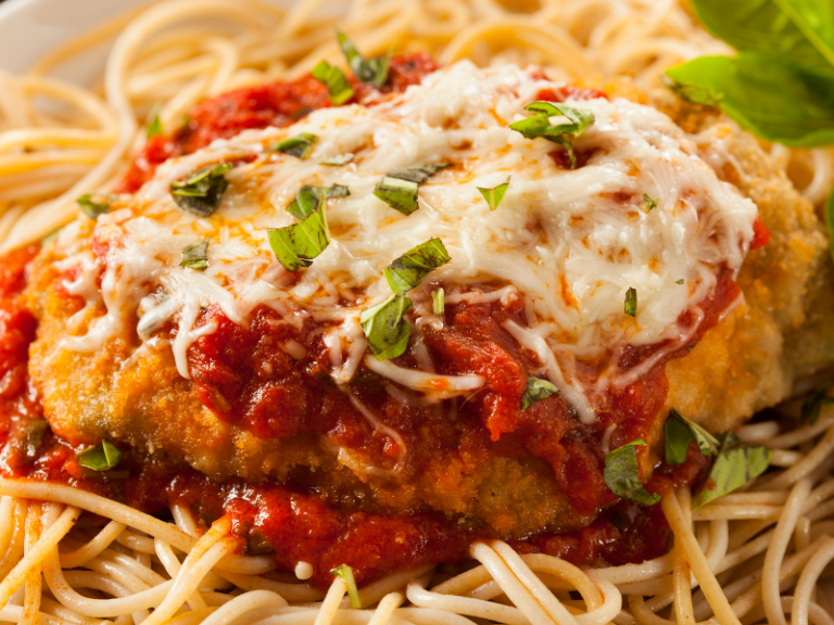 Chicken coated in breadcrumbs with tomato sauce and parmesan cheese melted on top over spaghetti noodles