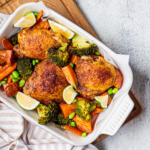 Oven baked chicken thighs with vegetables in a white dish