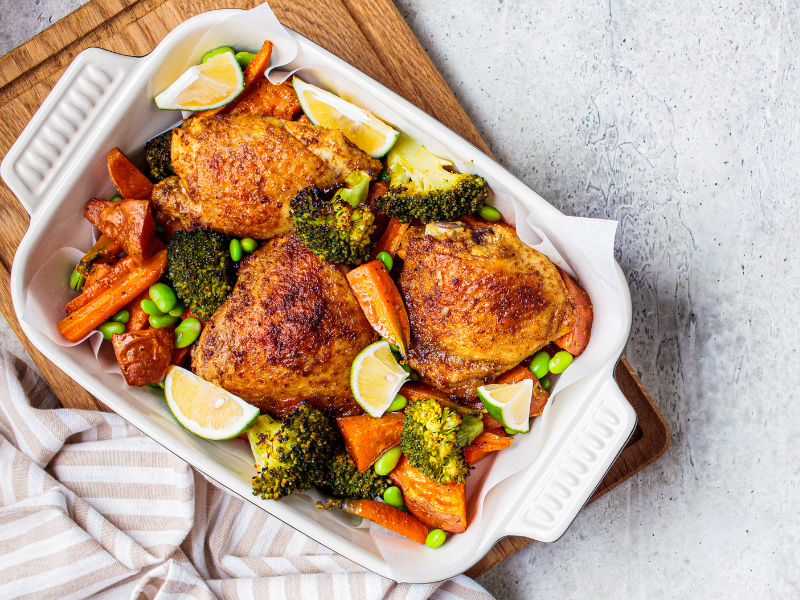 Oven baked chicken thighs with vegetables in a white dish